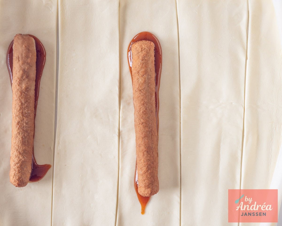 Strips of puff pastry with curry and a frikandel on top.