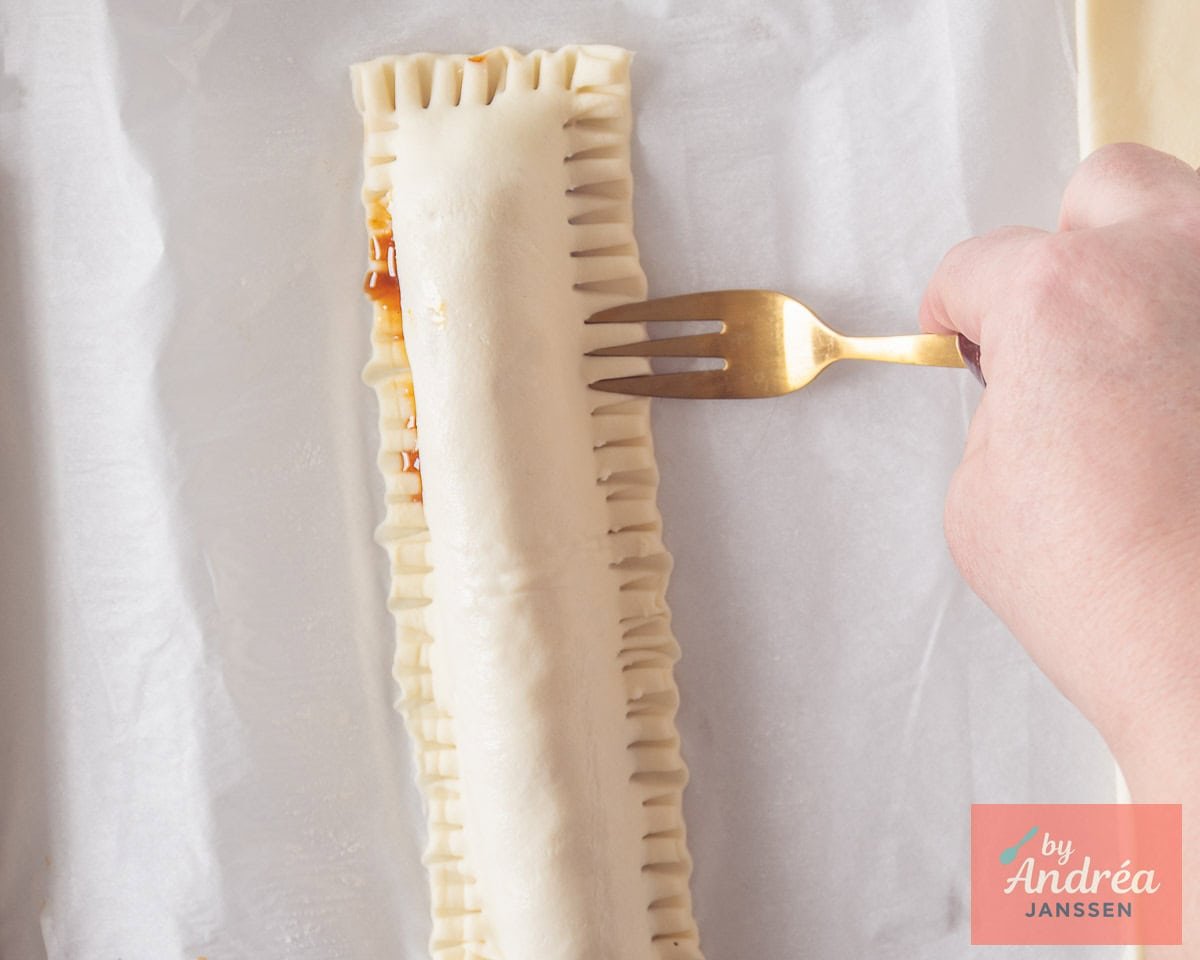 A frikandel roll with the edges pressed closed with a fork