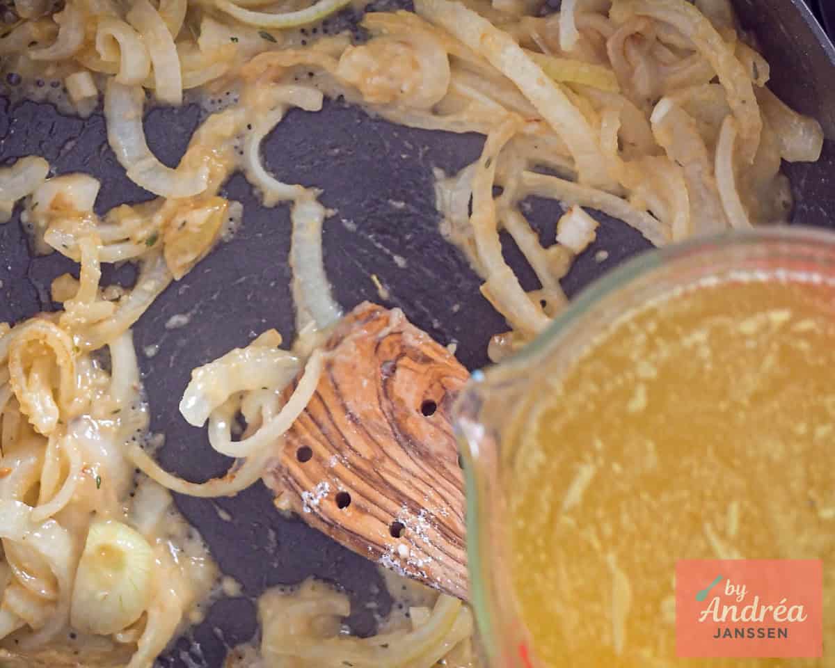 Broth is added to a pan with onion
