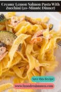 A portion of a white plate with tagliatelle, salmon flakes, zucchini, capers, and cream sauce. At the top is the text: Creamy Lemon Salmon Pasta with Zucchini (20-Minute Dinner)