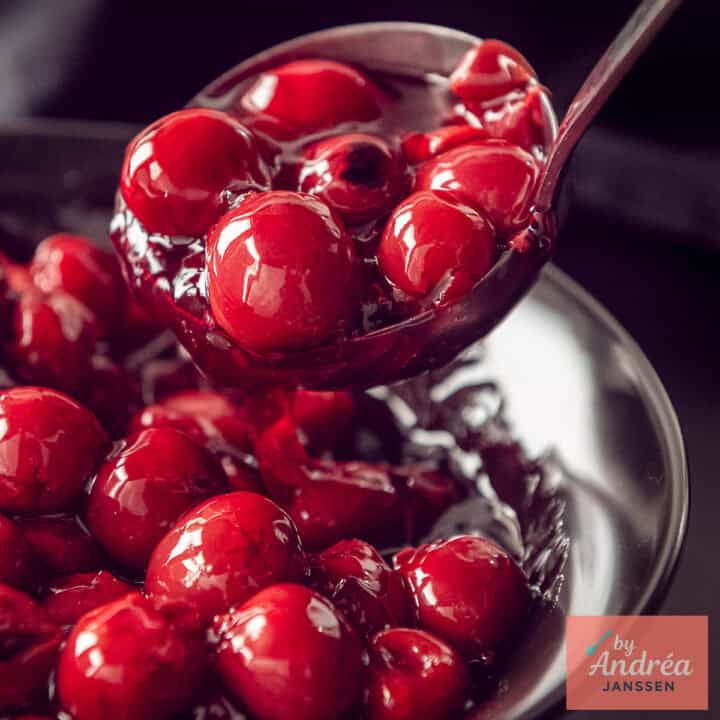 A square photo of a bowl of cherry pie filling being scooped out.
