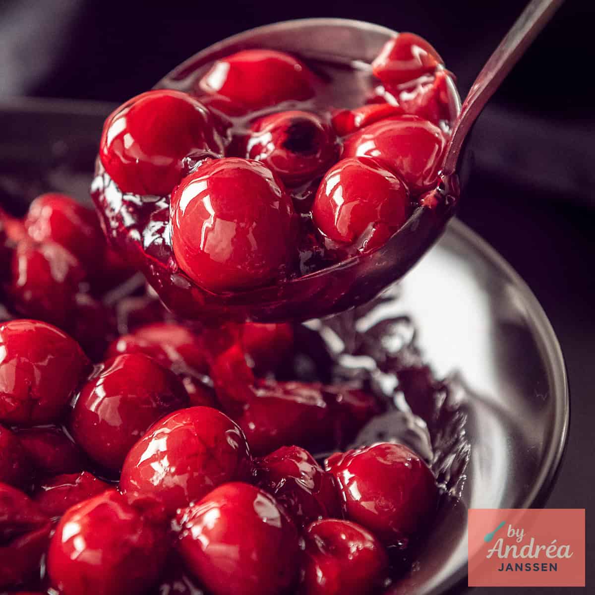 A square photo of a bowl of cherry pie filling being scooped out.