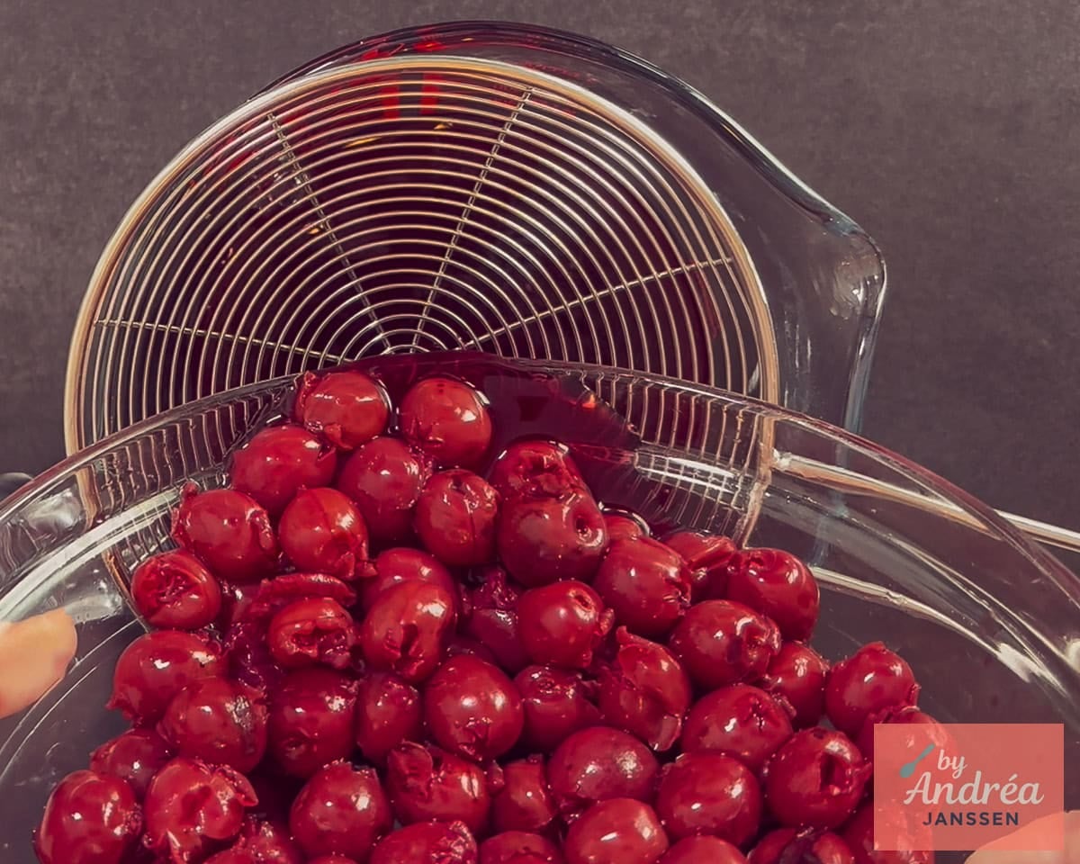 A jar of cherries is placed in a sieve.