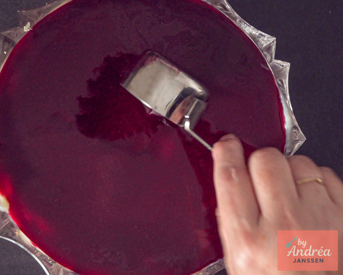 Red fruit jelly is poured over the trifle.