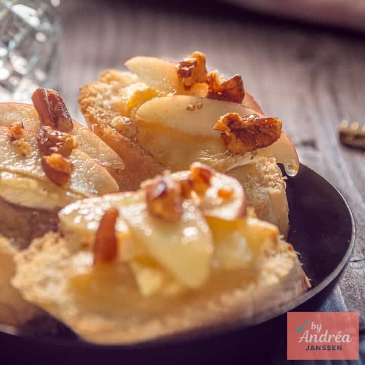 A black bowl with three slices of baguette with honey, apple, Brie and walnut