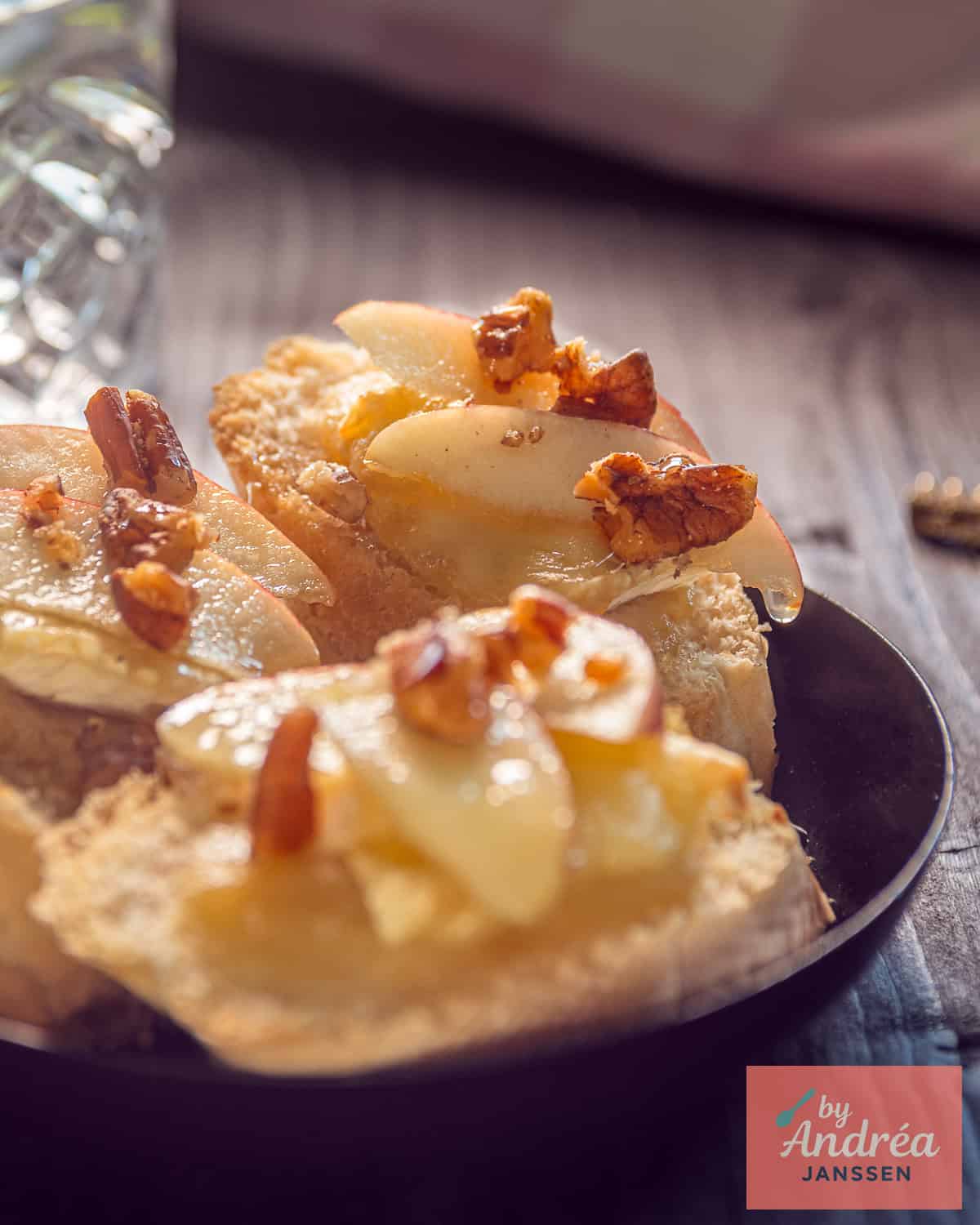 Three bruschetta in a black bowl with apple, Brie, walnut and honey.