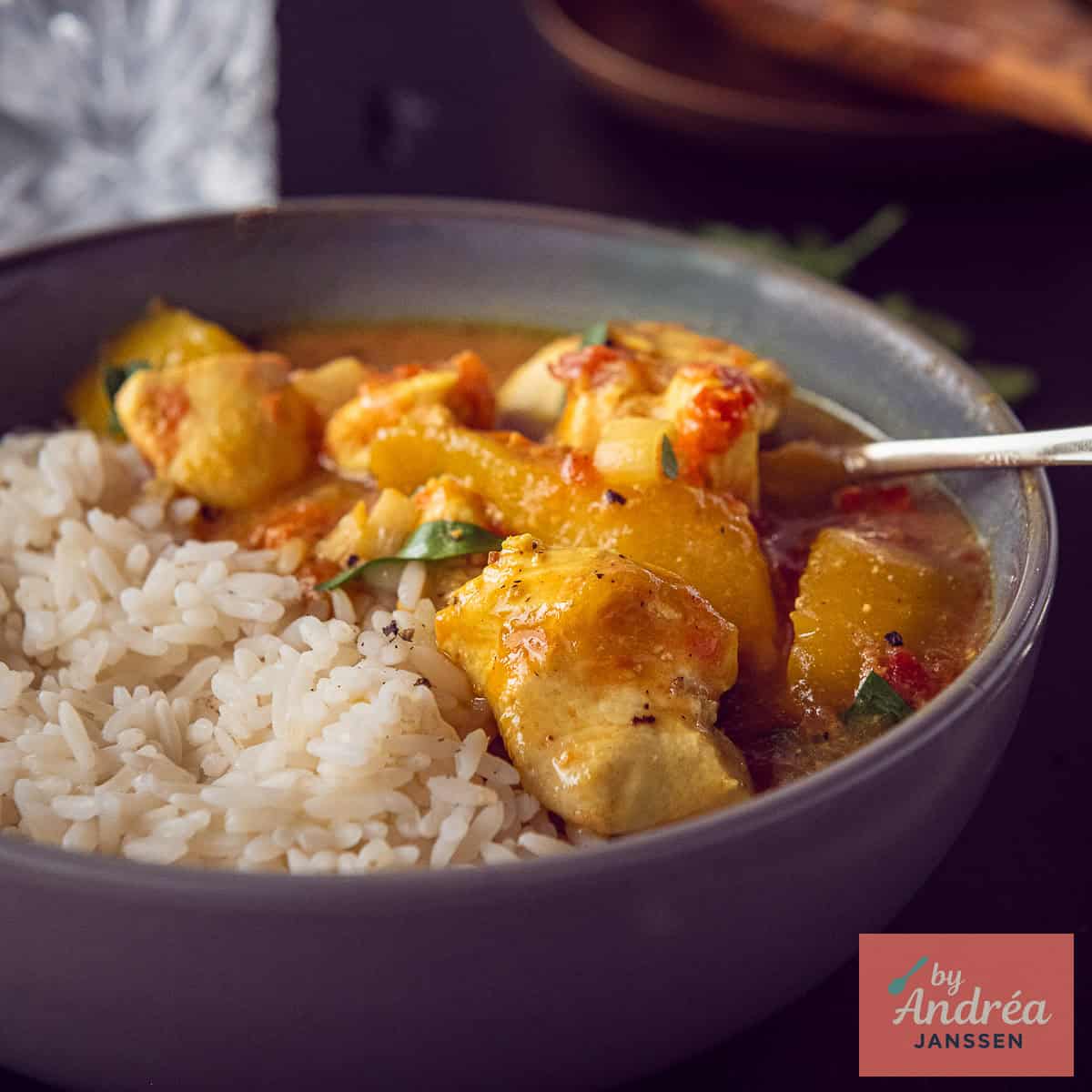 A square photo of a bowl of rice, chicken and mango curry