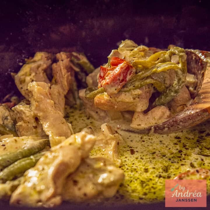 A square photo of a slow cooker with Tuscan chicken being scooped out of it.