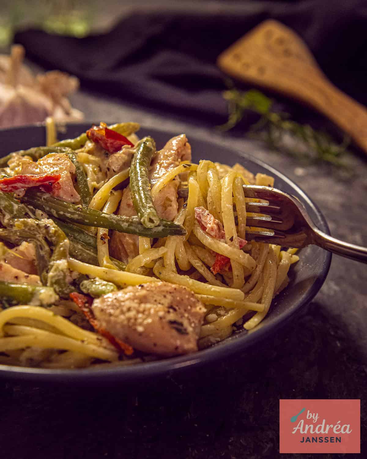 A gray plate with pasta and Tuscan chicken from the slow cooker with beans
