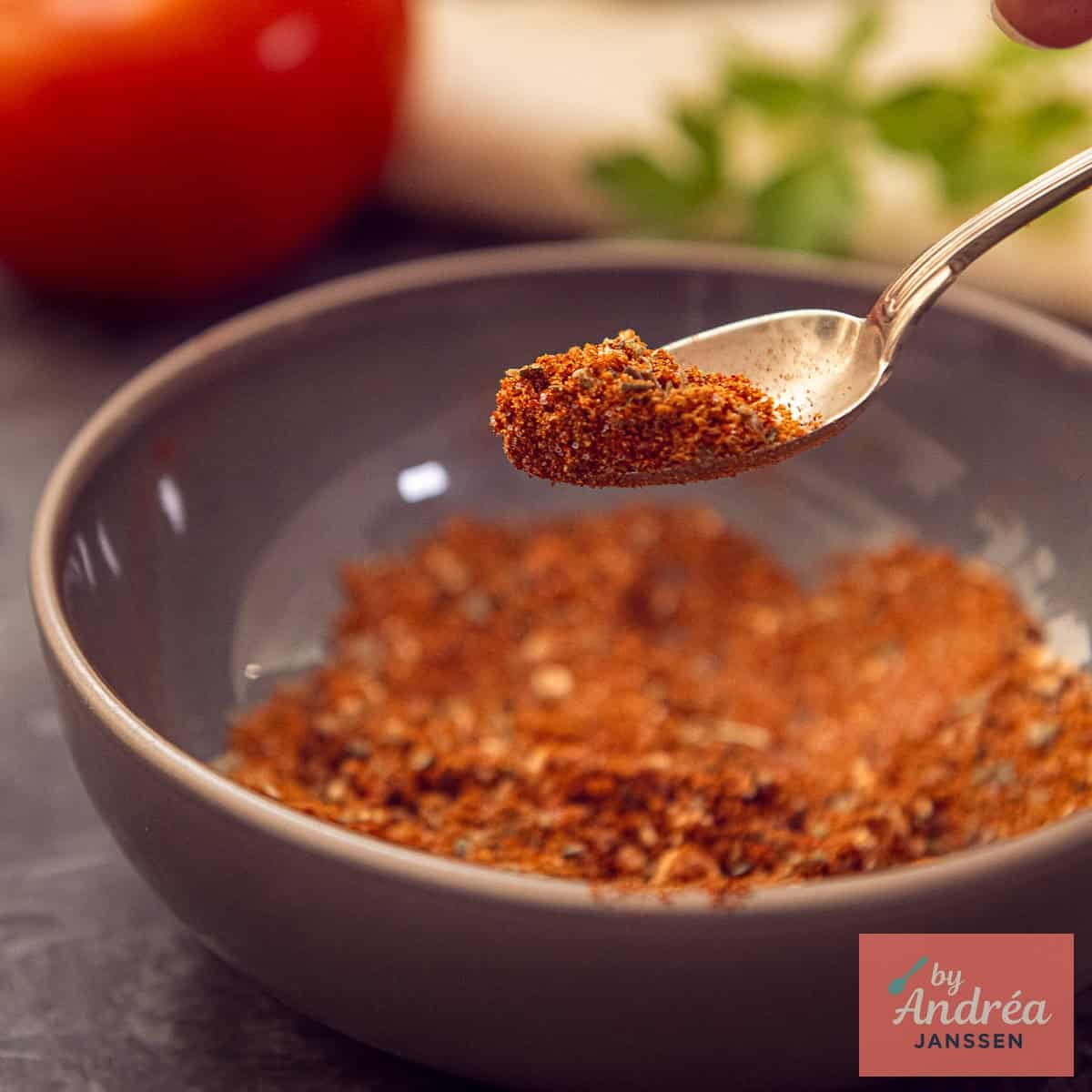 A square photo with a gray bowl of Mexican burrito spice mix without packets and bags
