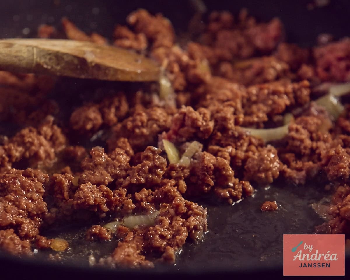 A frying pan in which ground beef with onion is browned.