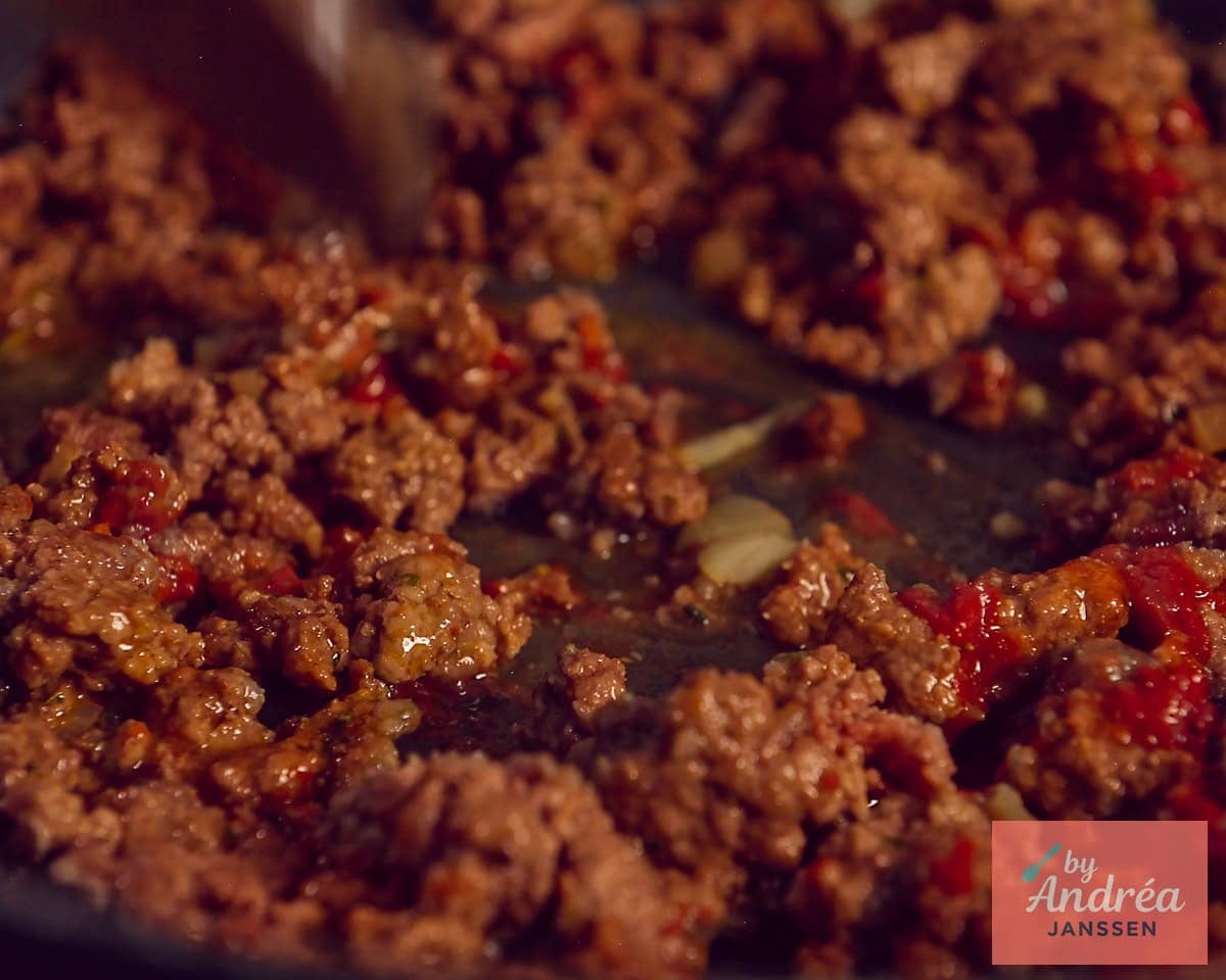 A frying pan with crumbly fried ground beef with seasonings such as tomato paste and onion
