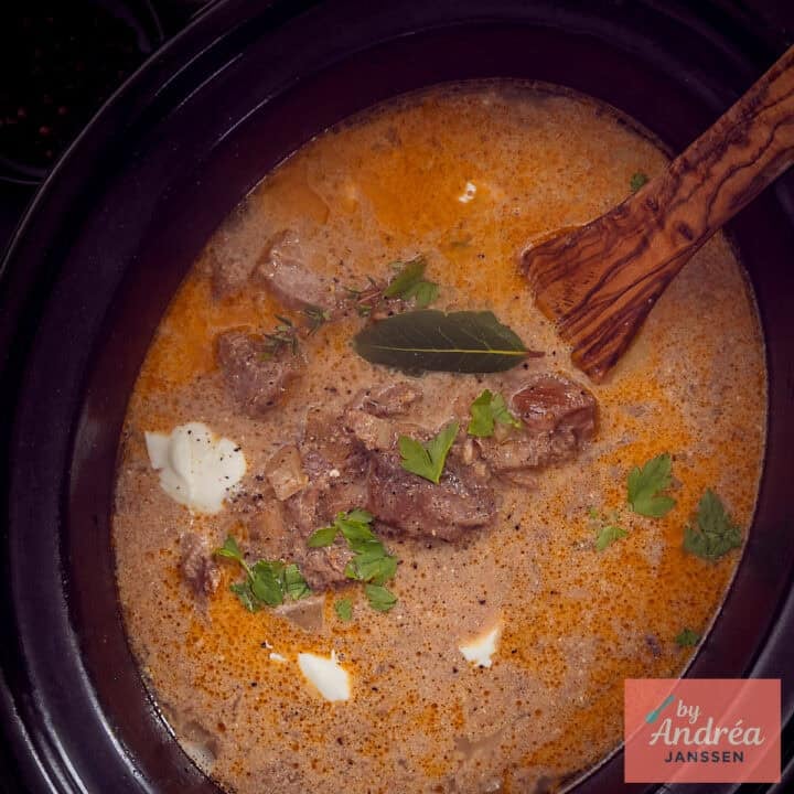 A square photo of part of a slow cooker filled with beef stroganoff.