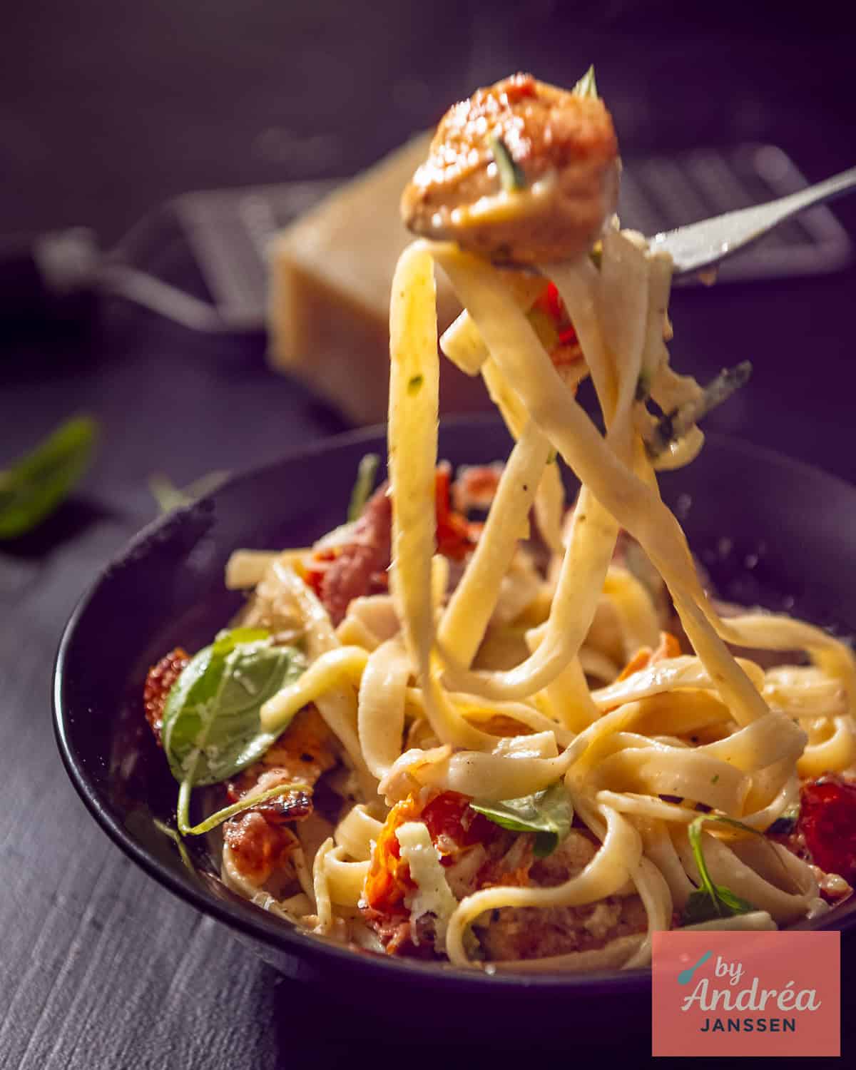 A dish of pasta with creamy sauce, chicken, sun-dried tomatoes, and bacon