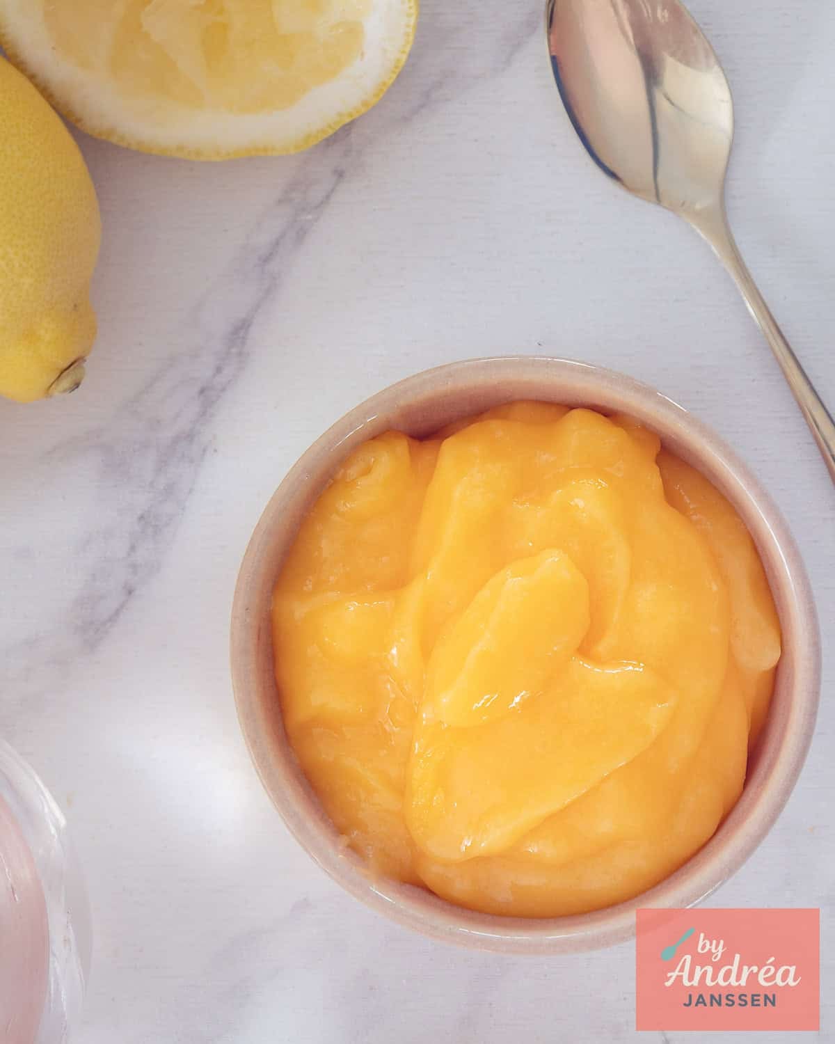 A photo from above of a bowl of lemon curd on a white background.