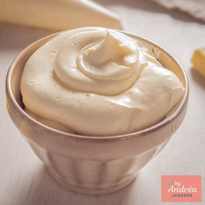 A square photo with a beige bowl of vanilla white chocolate buttercream.