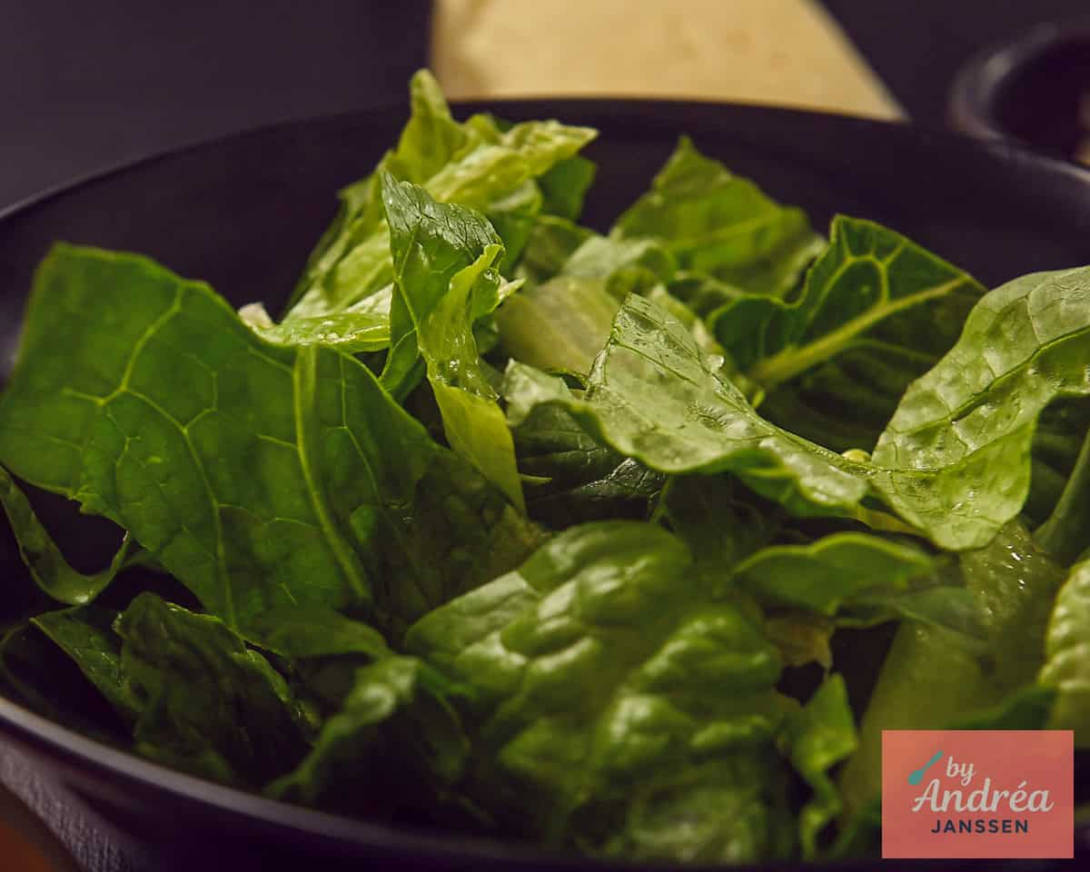 Romaine lettuce in pieces distributed over a black bowl