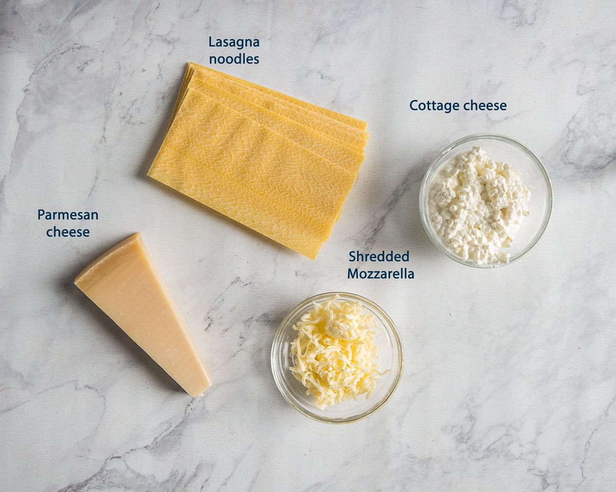 Lasagna noodles, cottage cheese, shredded mozzarella, and a wedge of Parmesan with English labels.
