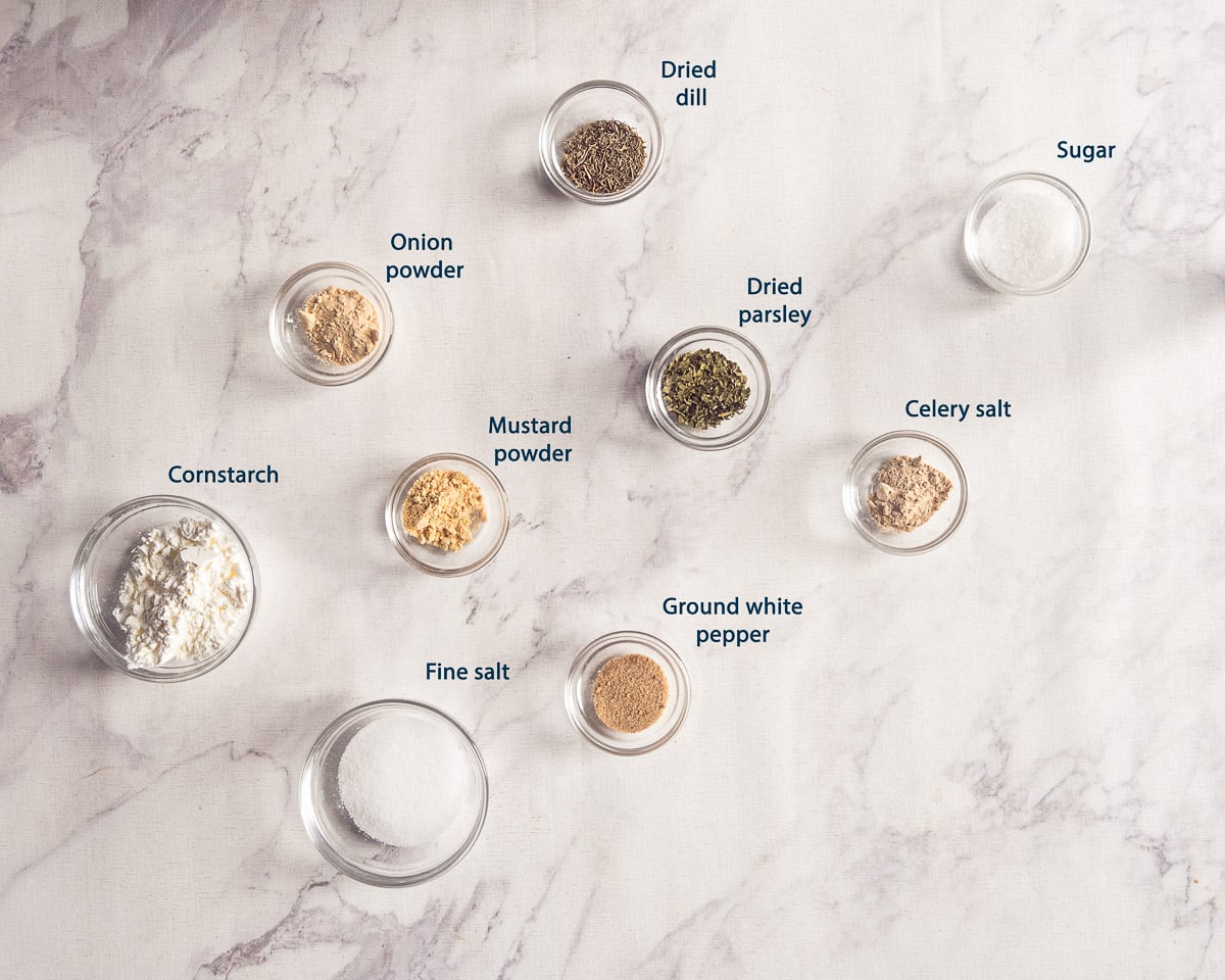 Ingredients for homemade Dutch fish seasoning: fine salt, cornstarch, celery salt, mustard powder, onion powder, sugar, white pepper, parsley, and dill
