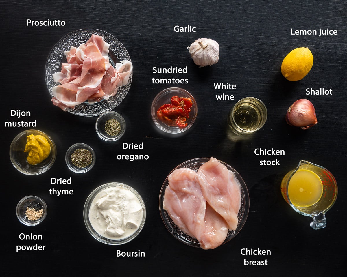 Ingredients for slow cooker Boursin chicken with crispy prosciutto arranged on a black surface, labeled in English.