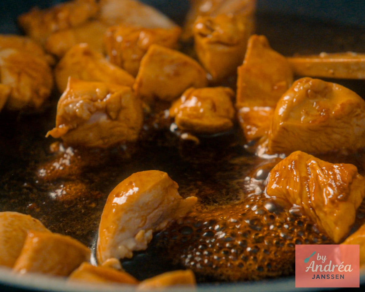 Chicken breast pieces coated in glossy, dark sweet soy sauce bubbling in a skillet.